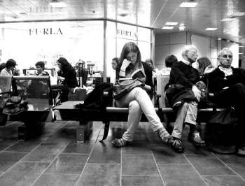 la donna sola legge, in attesa, nella sala d'aspetto di un aeroporto