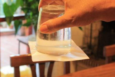 Un bicchiere d'acqua capovolto, con un foglio di carta. L'acqua non cade