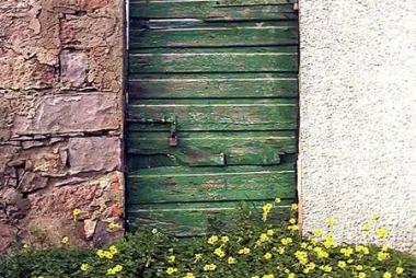 nel giardino dai fiori gialli, una porta. Il problema è sempre quello: cosa ci sarà dietro la porta? Fotografia di Guido Pegna