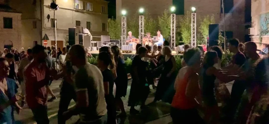 foto di una danza in piazza al suono dell'organetto, di notte.