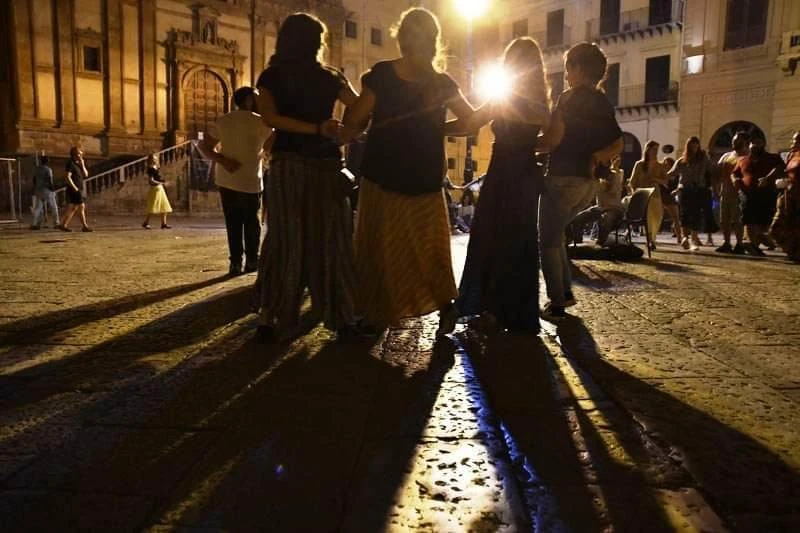 foto di una danza in piazza al suono dell'organetto, di notte.