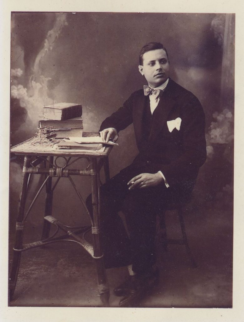 Foto di un'altra epoca: un uomo è seduto a un tavolino, con la penna in mano, guarda altrove con aria pensosa